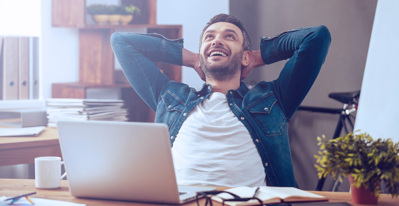 Picture of a man sitting in front of their computer and feeling happy after sending their job application